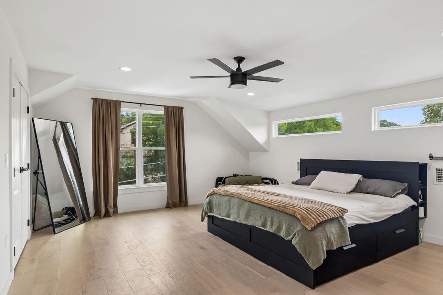 The primary bedroom is a sanctuary of light, featuring large windows that offer views of the surrounding greenery. The high ceilings and neutral palette enhance the room's airy feel, while the plush carpeting underfoot adds a layer of comfort.