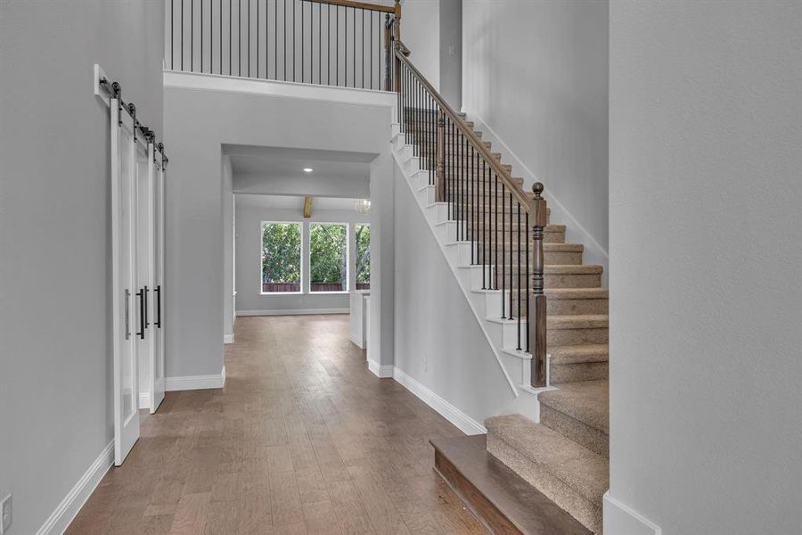 Foyer featuring a barn door, a towering ceiling, and hardwood / wood-style floors