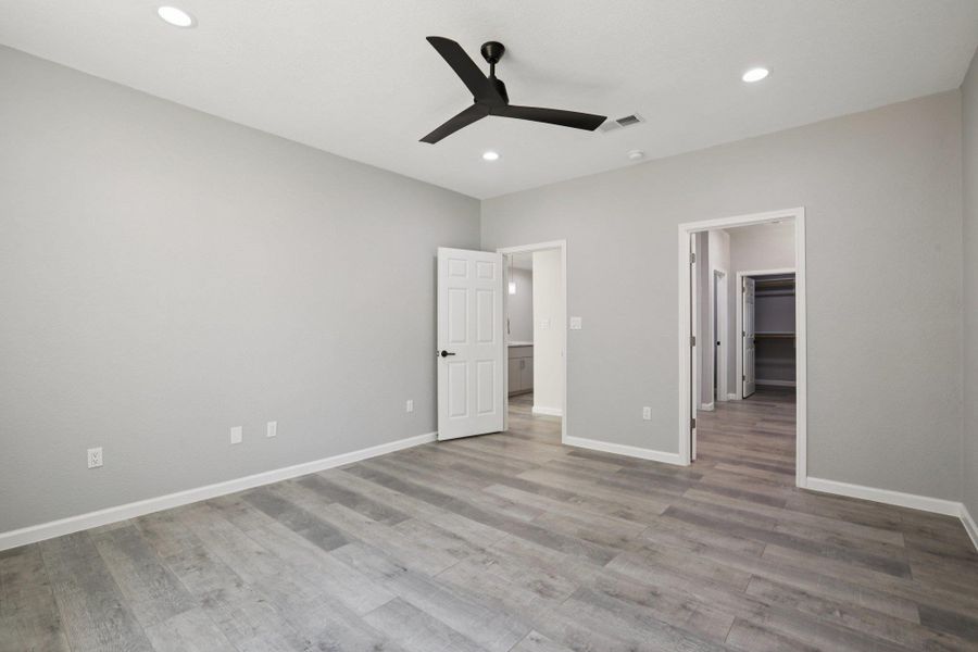 Primary Bedroom with ceiling fan, a walk in closet, recessed lighting, and light wood-type laminate flooring