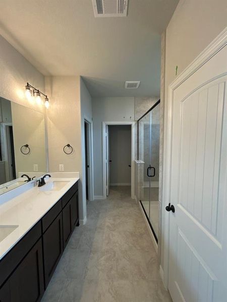 Modern bathroom featuring a dual vanity with dark wood cabinetry, light-toned countertops, and matte black fixtures Modern bathroom featuring a dual vanity with dark wood cabinetry, light-toned countertops, and matte black fixtures