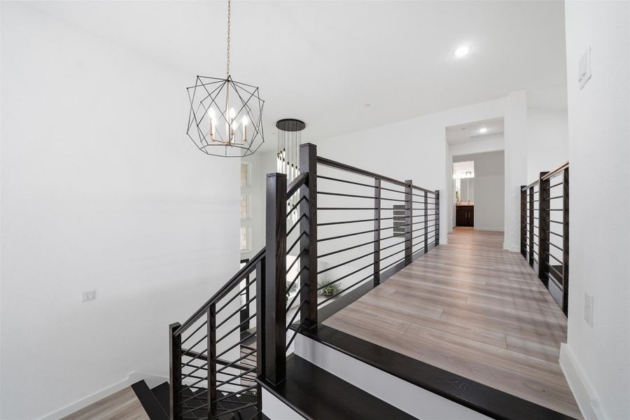 The interior features a modern light fixture, dark wood stair treads, and light wood flooring on the landing