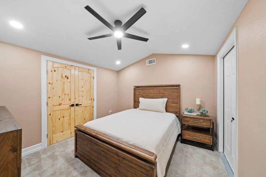 Third additional bedroom, carpeted and with large black five-blade ceiling fan and bright recessed LED lighting ensure the room feels airy and well-lit.