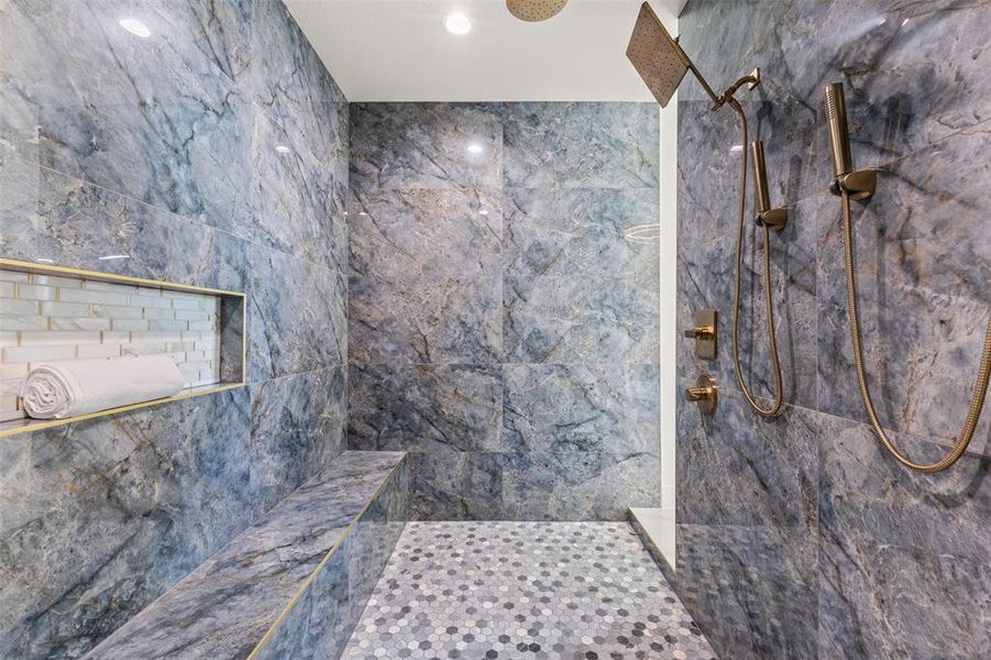 Walk-in shower with full-height stone-finish wall tiling, integrated bench seating, and a recessed niche with subway tile accent