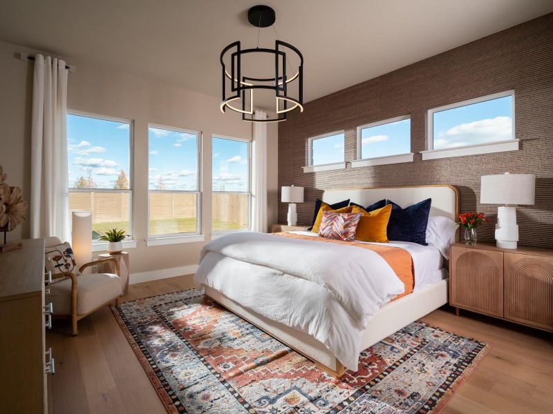 Bedroom with an accent wall, light wood finished floors, hanging lights, and wallpapered walls