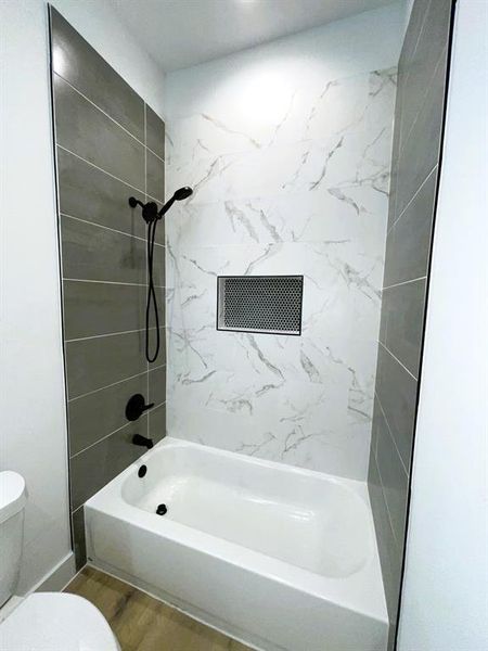 Bathroom featuring toilet, wood-type flooring, and tiled shower / bath