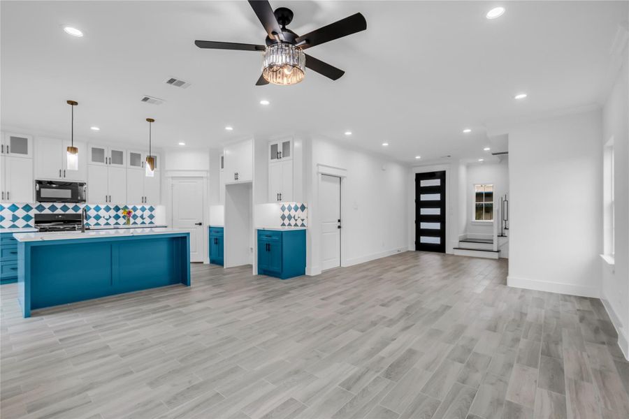 This open-concept living space seamlessly merges a modern kitchen featuring bold blue accents and sleek cabinetry with a spacious living and dining area, perfect for stylish entertaining and relaxed living.