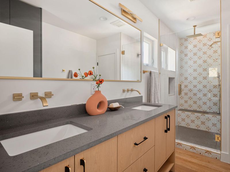 Full bath with double vanity, a shower stall, and light wood-type flooring Full bath with double vanity, a shower stall, and light wood-type flooring