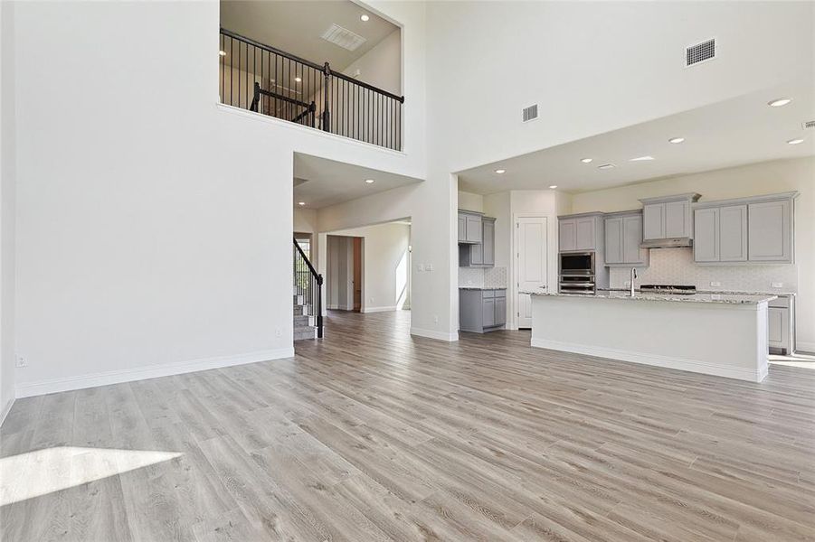 Unfurnished living room featuring light hardwood / wood-style floors, sink, and a high ceiling