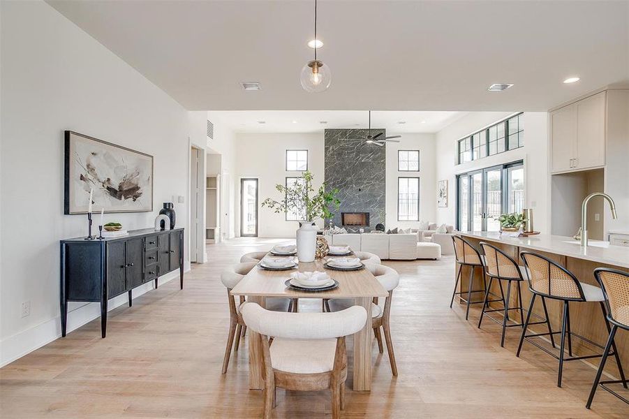 Dining space with visible vents, light wood finished floors, a premium fireplace, recessed lighting, and ceiling fan