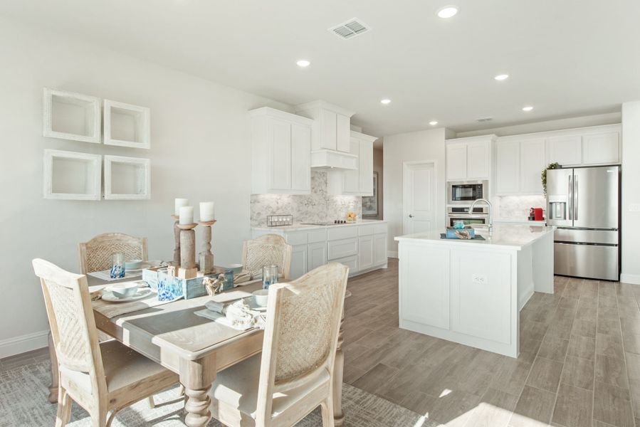 Open-concept kitchen and dining area with white cabinets, center island, stainless appliances, and wood-look floors