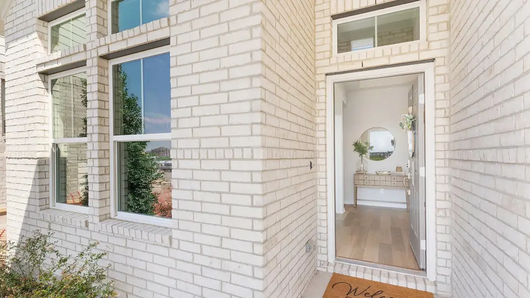 A cream brick facade welcomes guests through a wide entry, revealing a warm, inviting foyer. A cream brick facade welcomes guests through a wide entry, revealing a warm, inviting foyer.