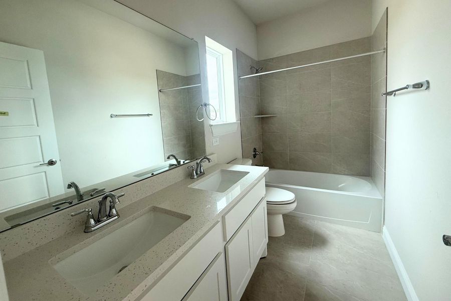 Bathroom featuring a dual vanity with undermount sinks, stone-finish countertop, and chrome fixtures Bathroom featuring a dual vanity with undermount sinks, stone-finish countertop, and chrome fixtures