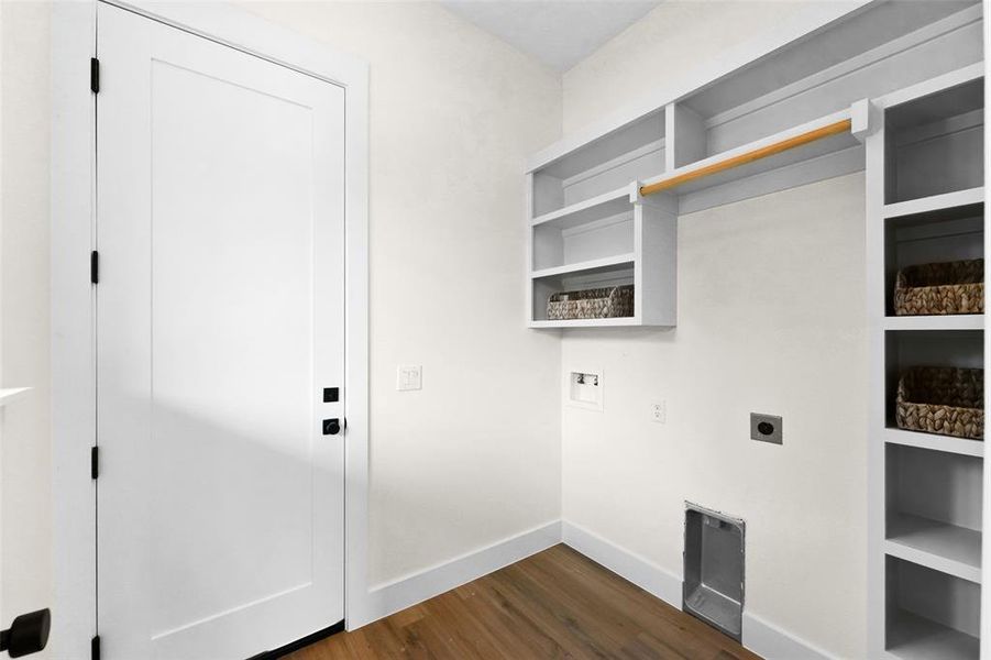Dedicated laundry space featuring white built-in shelving, a natural wood hanging rod, and wood-finish flooring