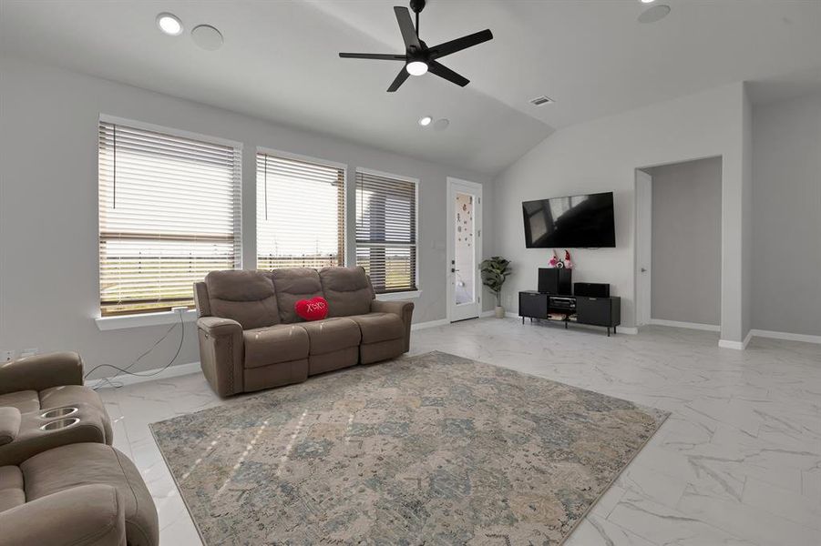 Living room with vaulted ceiling, marble finish floor, and recessed lighting