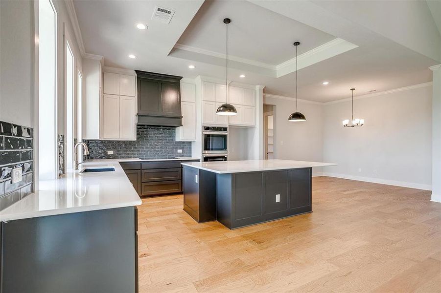 Kitchen with premium range hood, a center island, stainless steel double oven, and light hardwood / wood-style floors