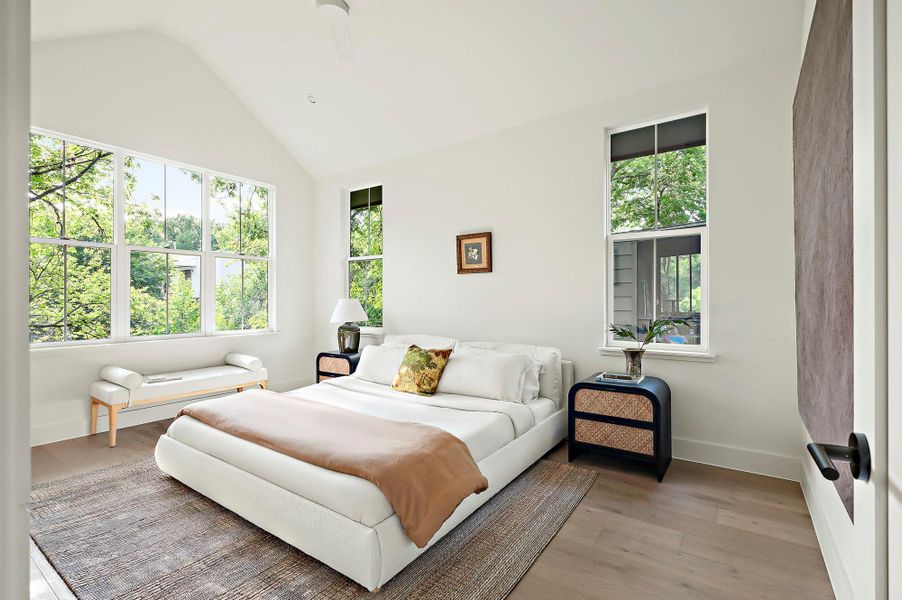 Bedroom featuring light wood-style floors, baseboards, and high vaulted ceiling