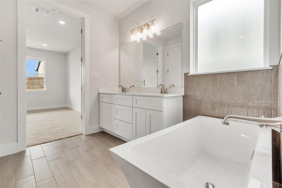 Indulge in a tranquil bathing experience in this modern primary bath with double vanity and large soaking tub.