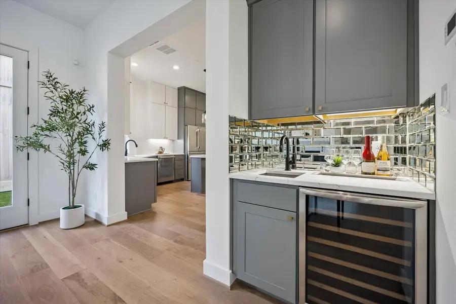 A distinctive mirrored backsplash elevates this wet bar, conveniently located just off the living area and perfect for entertaining.