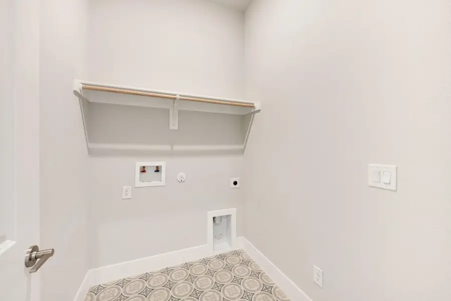 Laundry room with wall shelf, washer hookups, dryer vent, and patterned tile floor