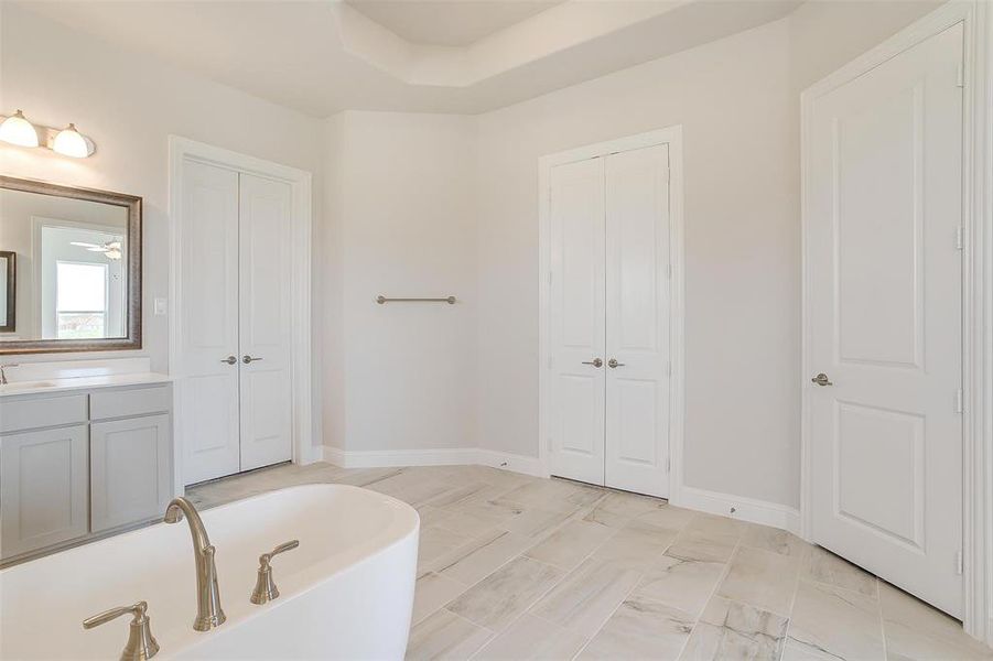 Bathroom featuring vanity, tile patterned floors, ceiling fan, a raised ceiling, and a bathtub