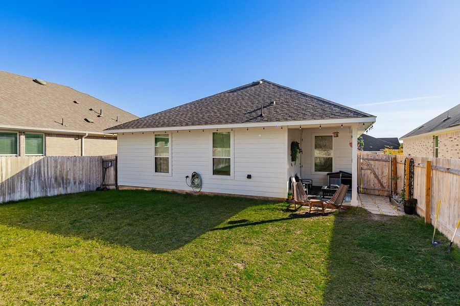 Back of property featuring a fenced backyard, a patio, and a shingled roof
