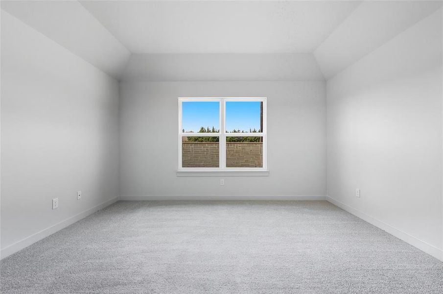 Empty room with light colored carpet and vaulted ceiling