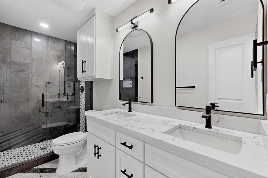 Bathroom featuring double vanity and a marble finish shower