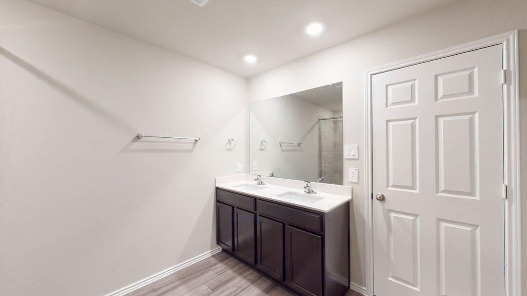 Double vanity offers ample space, illuminated by recessed lighting.