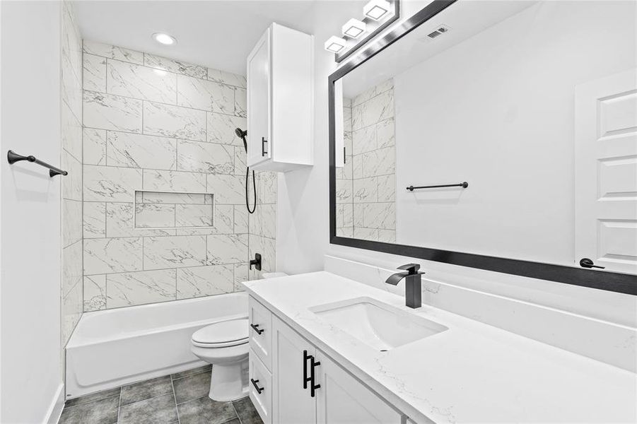 Full bathroom with vanity, tiled shower / bath combo, and toilet