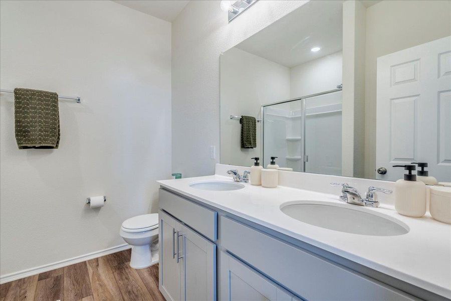 Primary bathroom features double sinks, LVP, walk-in shower and linen closet Primary bathroom features double sinks, LVP, walk-in shower and linen closet