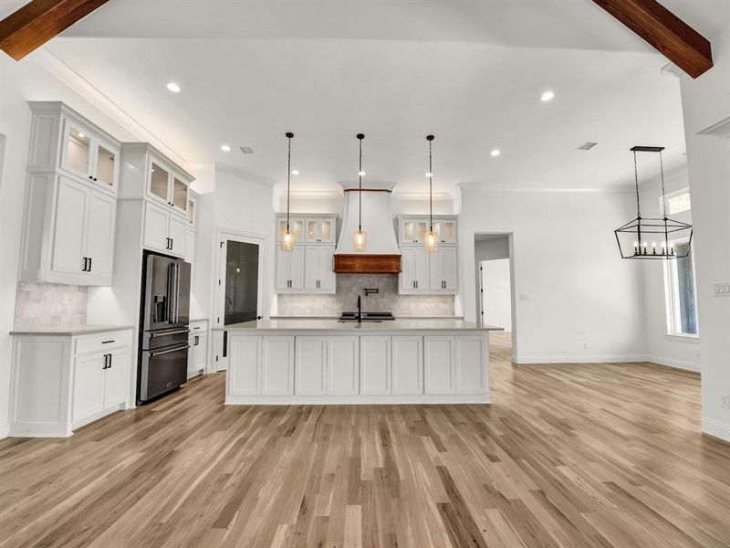Kitchen with stainless steel fridge, a sink, light countertops, premium range hood, and beam ceiling Kitchen with stainless steel fridge, a sink, light countertops, premium range hood, and beam ceiling