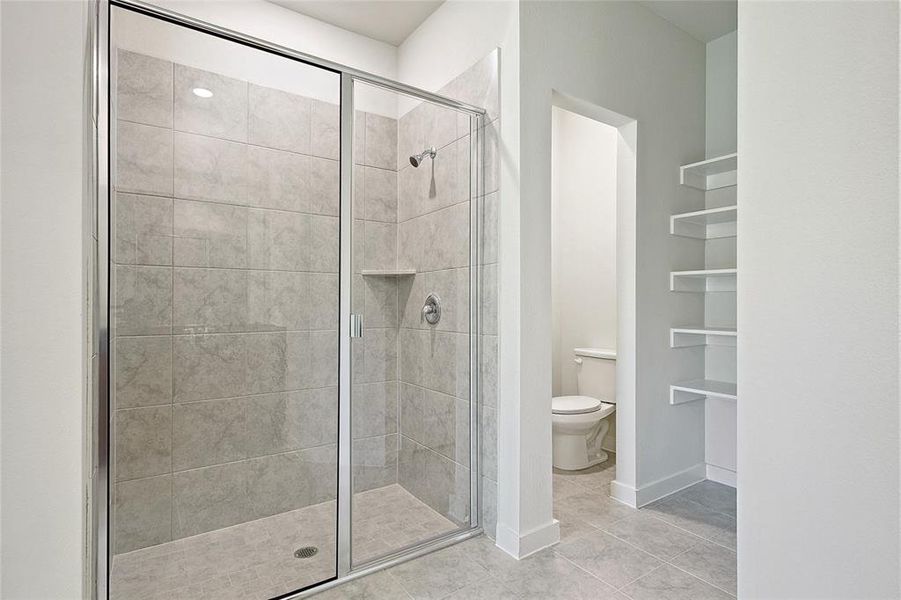 Bathroom featuring walk in shower, tile patterned flooring, and toilet