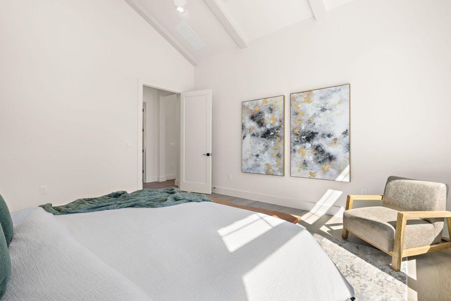 Bedroom featuring high vaulted ceiling, beam ceiling, baseboards, and wood finished floors