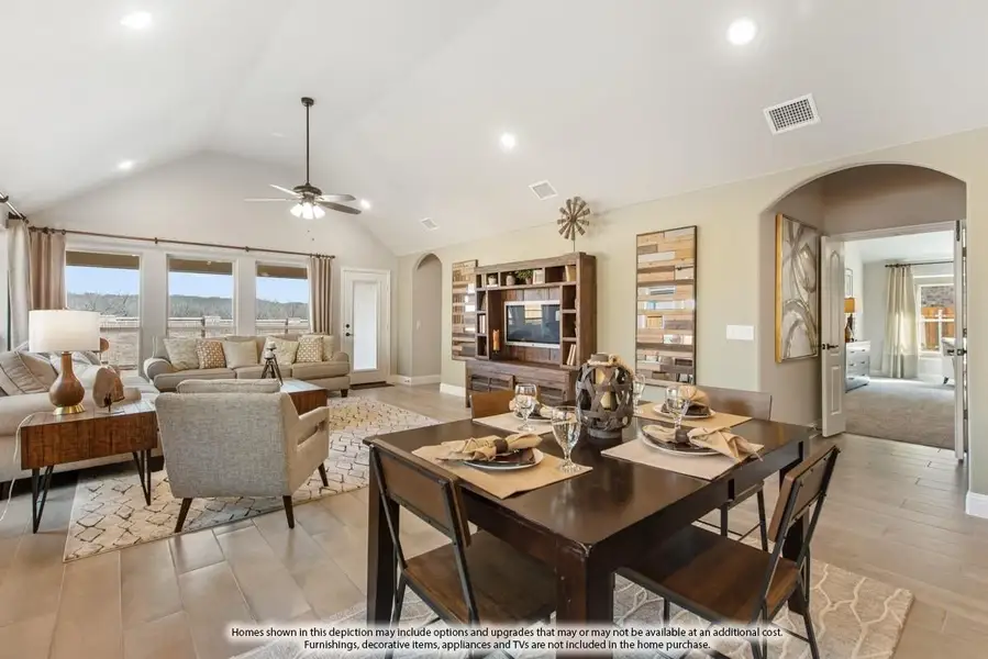Open-concept dining and living area with vaulted ceiling, ceiling fan, wood entertainment center, and tile floors