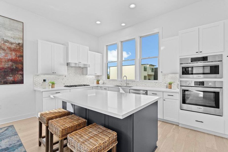 Kitchen featuring white cabinets, a kitchen breakfast bar, light wood-style flooring, and recessed lighting Kitchen featuring white cabinets, a kitchen breakfast bar, light wood-style flooring, and recessed lighting