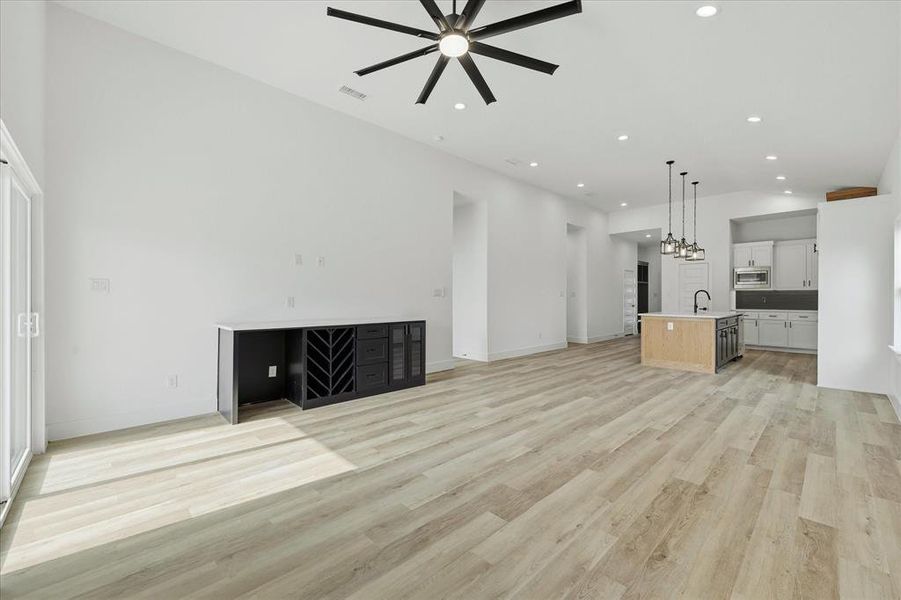 Unfurnished living room with vaulted ceiling, light wood-style flooring, ceiling fan, and recessed lighting