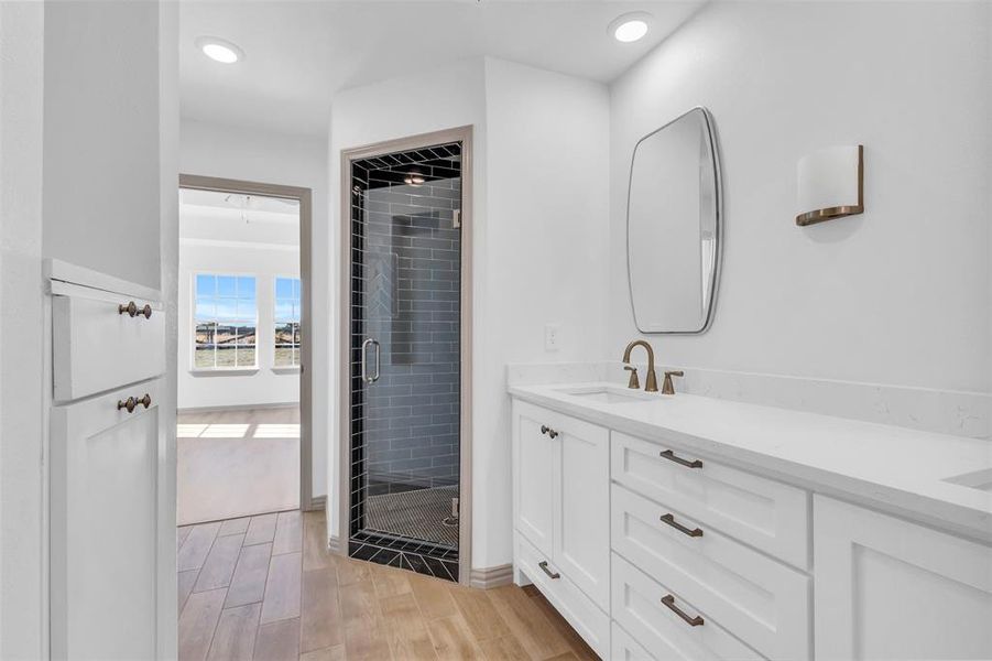 Bathroom featuring a shower with door, vanity, and hardwood / wood-style flooring