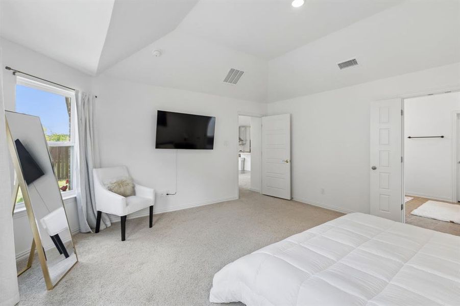 Carpeted bedroom featuring a vaulted ceiling and a window with a white frame