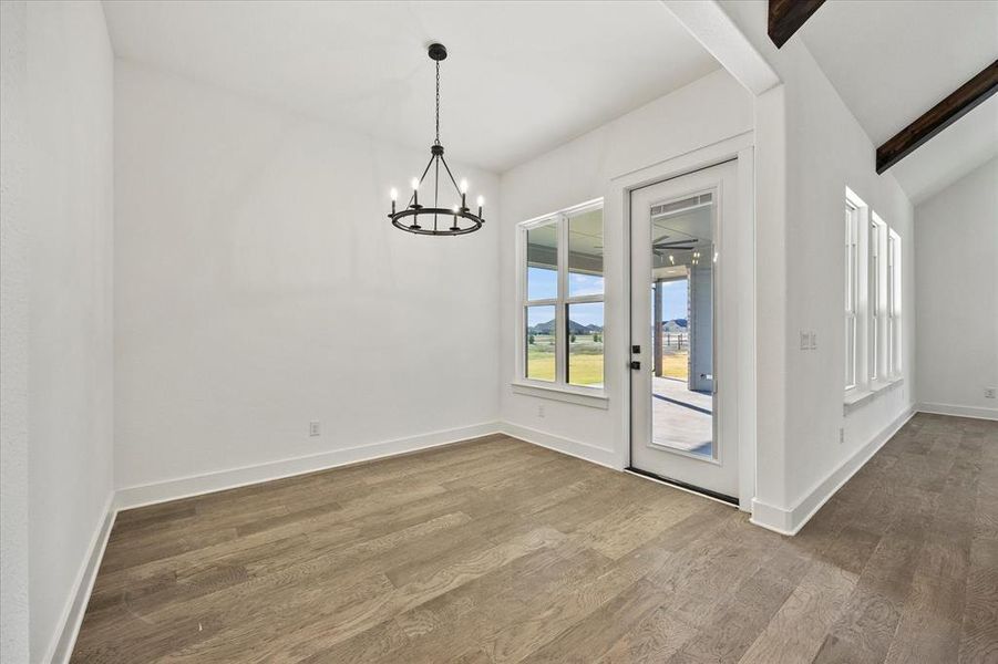 Unfurnished dining area featuring hardwood / wood-style flooring, vaulted ceiling with beams, and a chandelier