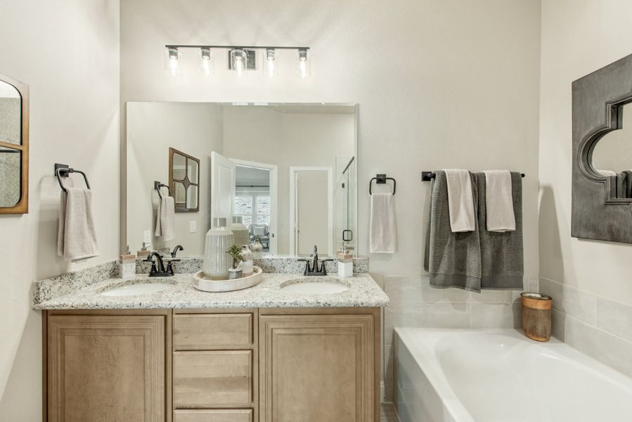 Bathroom with double sink vanity, granite countertop, wood cabinets, and soaking tub