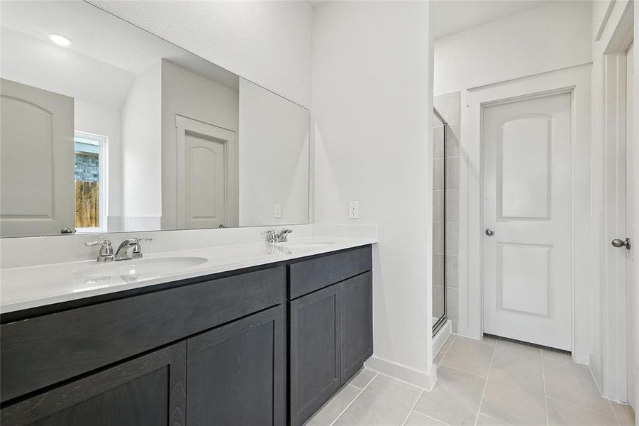 Full bath featuring double vanity, a shower stall, and light tile patterned floors