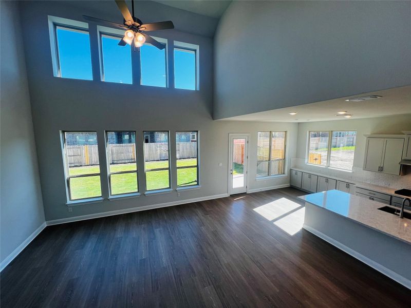 Unfurnished living room with a high ceiling, dark wood-style flooring, and ceiling fan