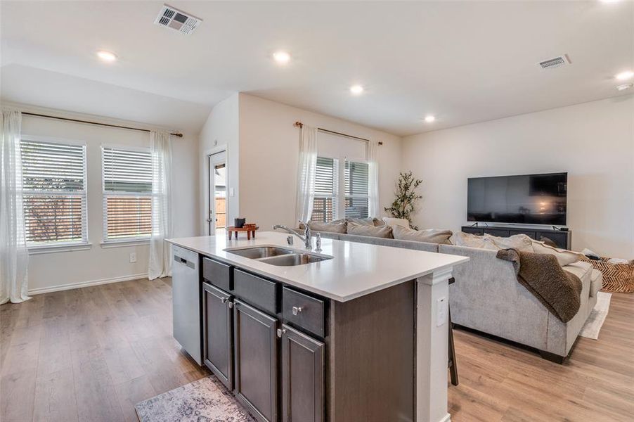 Kitchen with a center island with sink, recessed lighting, light wood finished floors, open floor plan, and dark brown cabinetry