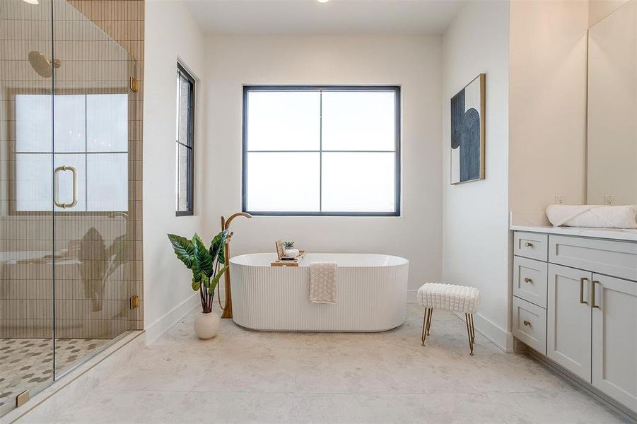 Full bath featuring baseboards, a freestanding bath, a stall shower, and vanity