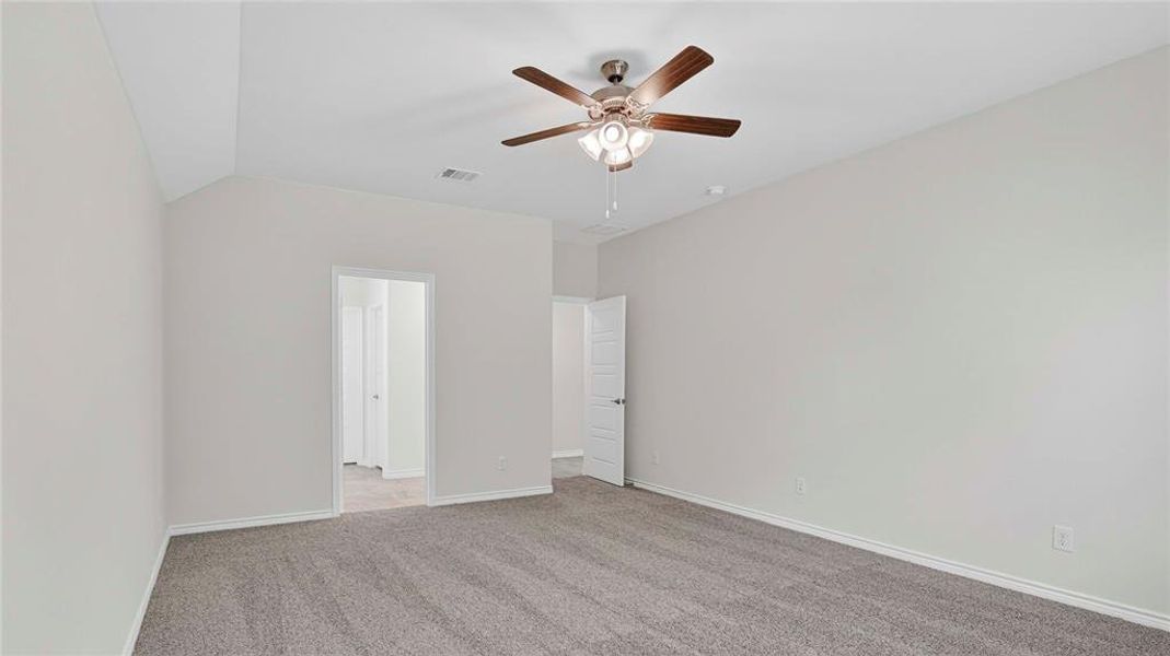 Spacious room featuring vaulted ceiling, neutral wall tones, and gray carpeting