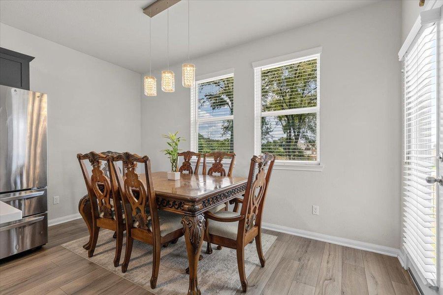 Natural light streams through large windows onto smooth wood-plank flooring.