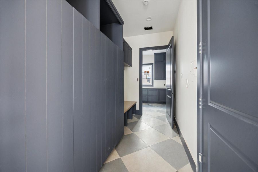 MUD ROOM - Custom built-ins pair with vertical panel detailing and wood bench seating, while patterned tile flooring adds durability and visual interest. Thoughtful storage and a clean, connected layout create a mud room designed to handle everyday use without sacrificing style. -- Construction as of 1/5/26