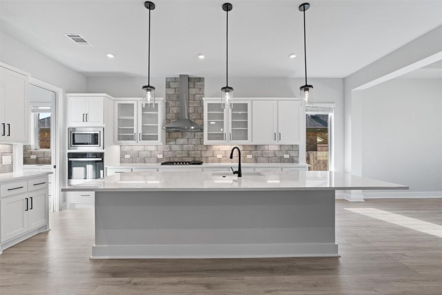 Kitchen featuring glass insert cabinets, white cabinetry, backsplash, light stone counters, and recessed lighting