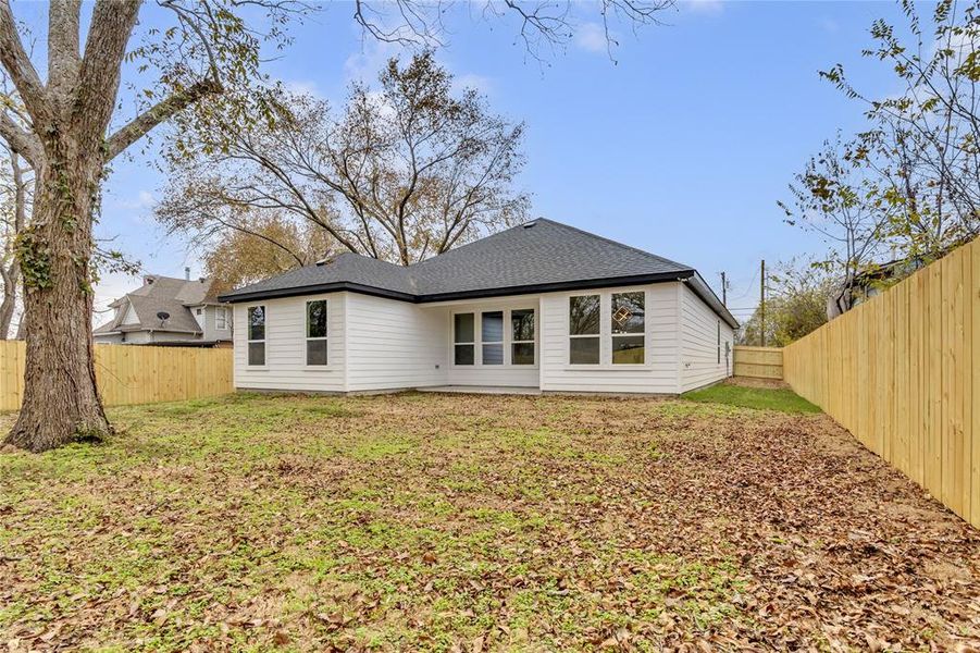 Rear view of house with a fenced backyard and roof with shingles