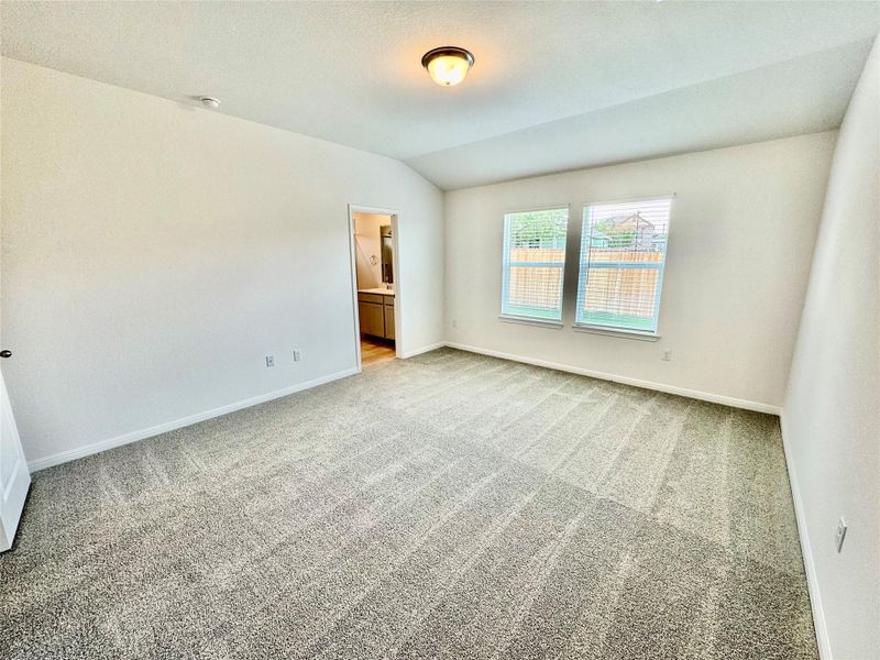Carpeted spare room featuring vaulted ceiling and baseboards Carpeted spare room featuring vaulted ceiling and baseboards